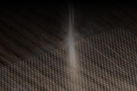 Laser beam drilling micro-holes into a wooden panel